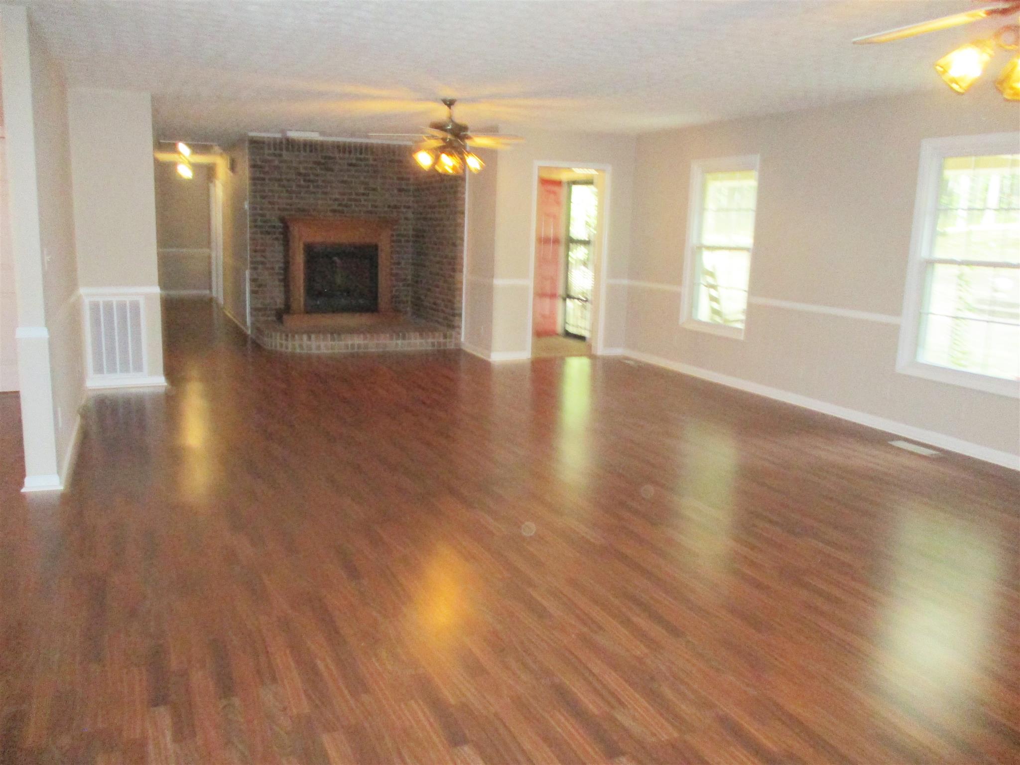 1073 West Point Road Lawrenceburg, TN 38464 - Photo 13 of 24 an empty room with wooden floor fireplace and windows