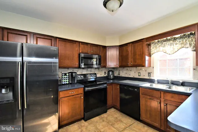 a kitchen with stainless steel appliances granite countertop a sink a stove a microwave a refrigerator a counter space and cabinets