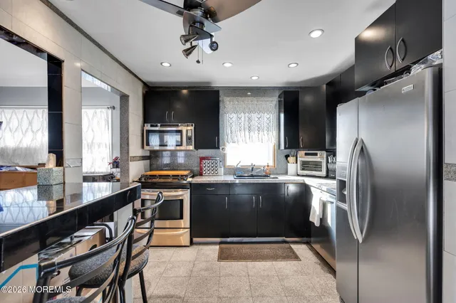 a kitchen with stainless steel appliances granite countertop a refrigerator a sink a stove and island