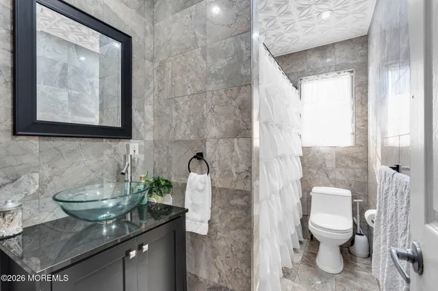 a bathroom with a granite countertop sink a toilet and a mirror