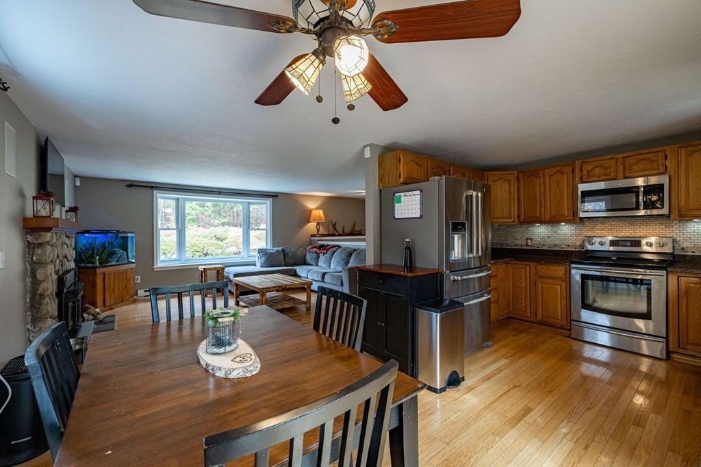 198 Lower Gore Road Webster, MA 01570 - Photo 11 of 41 a kitchen with stainless steel appliances granite countertop a stove top oven a refrigerator a dining table and chairs with wooden floor
