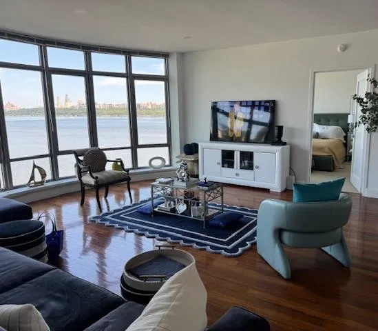 a living room with furniture a rug and a floor to ceiling window