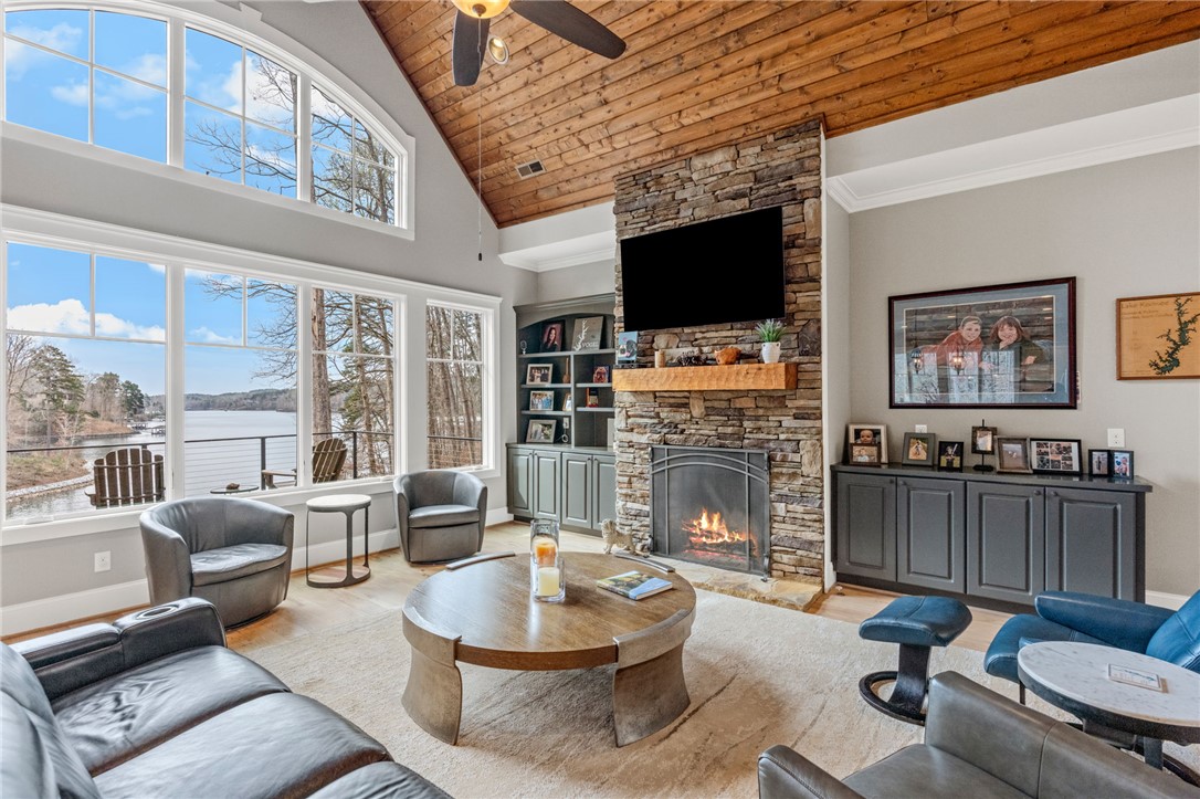 827 Top Ridge Drive Sunset, SC 29685 - Photo 8 of 44 This living room features a captivating stone fireplace, high wood ceilings, and large windows with lake views.