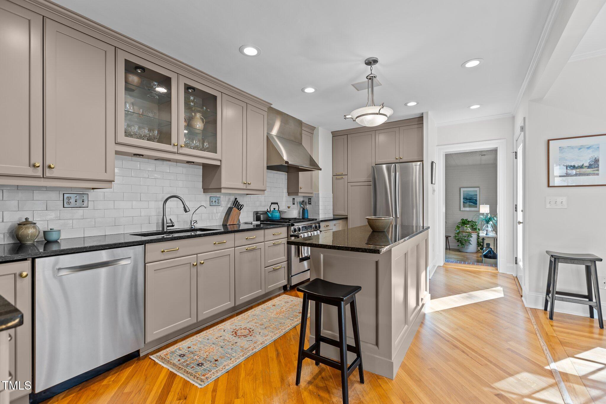 2706 Stuart Drive Durham, NC 27707 - Photo 8 of 26 a kitchen with stainless steel appliances kitchen island granite countertop a refrigerator a stove a sink dishwasher and white cabinets with wooden floor