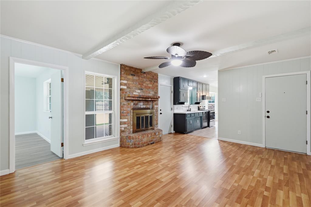 837 Springdale Road Bedford, TX 76021 - Photo 6 of 28 Spacious living area featuring wood-finish flooring, a brick fireplace with a metal insert, and a ceiling fan