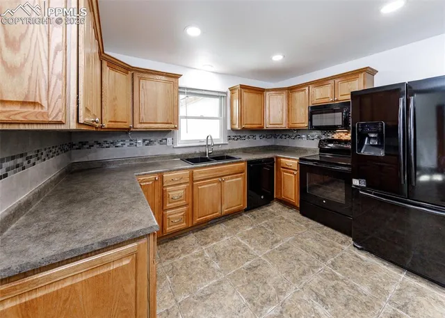 a kitchen with stainless steel appliances granite countertop a sink a stove and a refrigerator