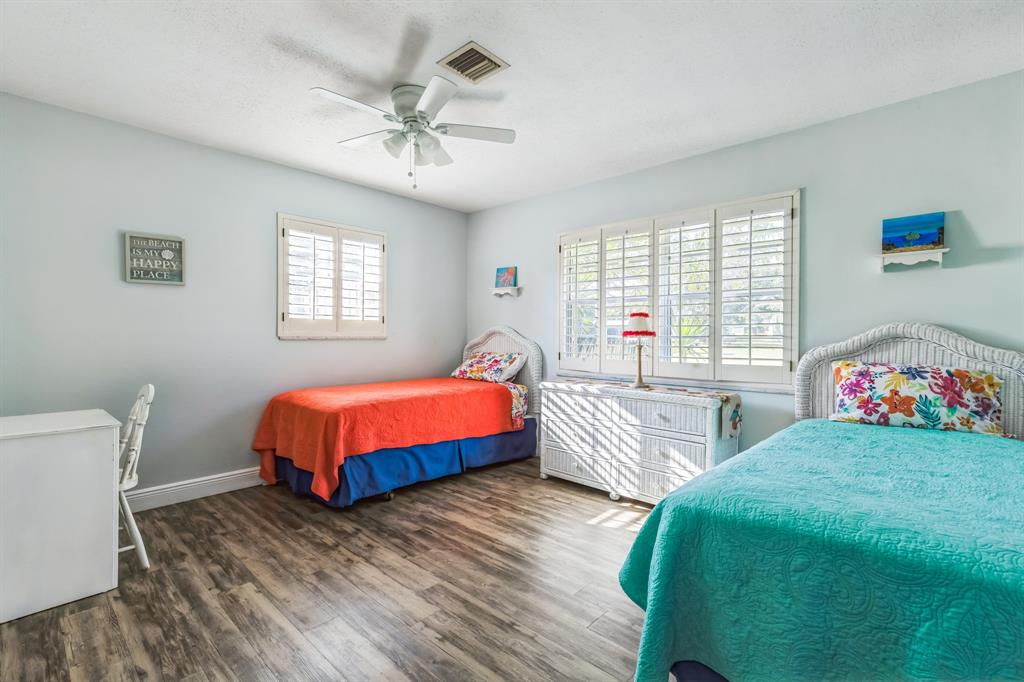 1153 Southeast Dolphin Drive Stuart, FL 34996 - Photo 16 of 31 a spacious bedroom with a bed a chandelier and a dresser
