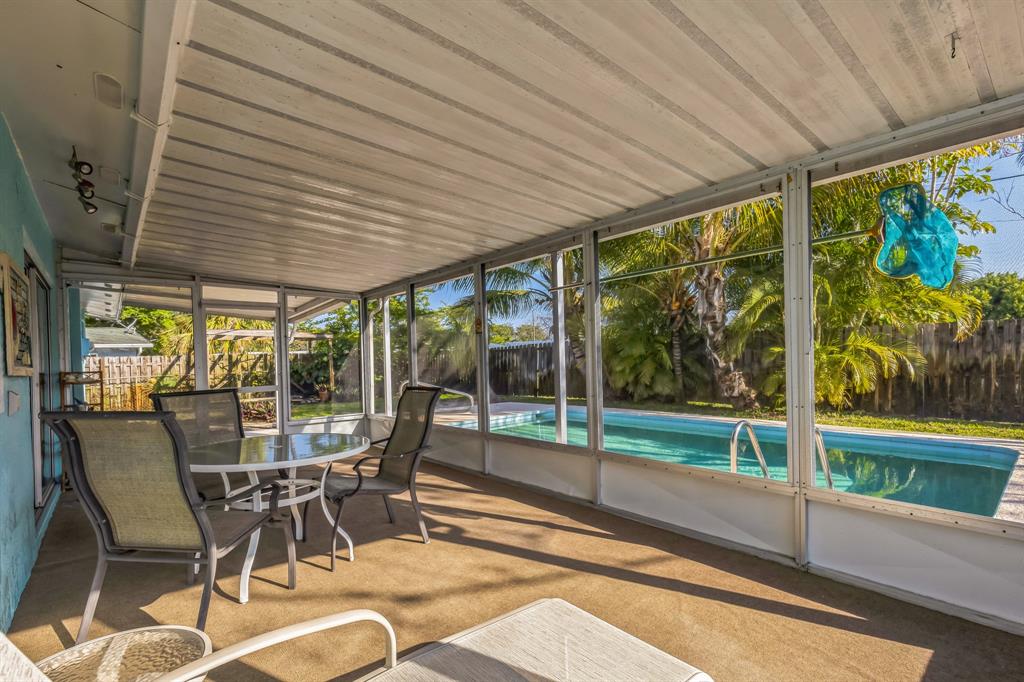 1153 Southeast Dolphin Drive Stuart, FL 34996 - Photo 27 of 31 a view of a patio with table and chairs potted plants and floor to ceiling window with garden view