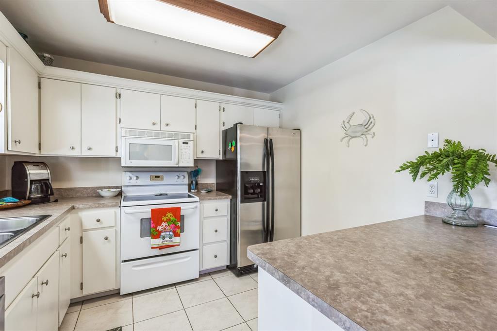 1153 Southeast Dolphin Drive Stuart, FL 34996 - Photo 9 of 31 a kitchen with stainless steel appliances granite countertop a stove a refrigerator and a white cabinets