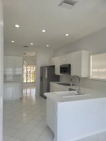 a kitchen with white cabinets and wooden floor