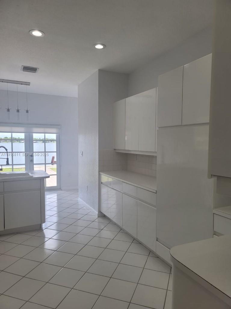 14765 Southwest 132nd Place Miami, FL 33186 - Photo 35 of 48 a kitchen with white cabinets and wooden floor