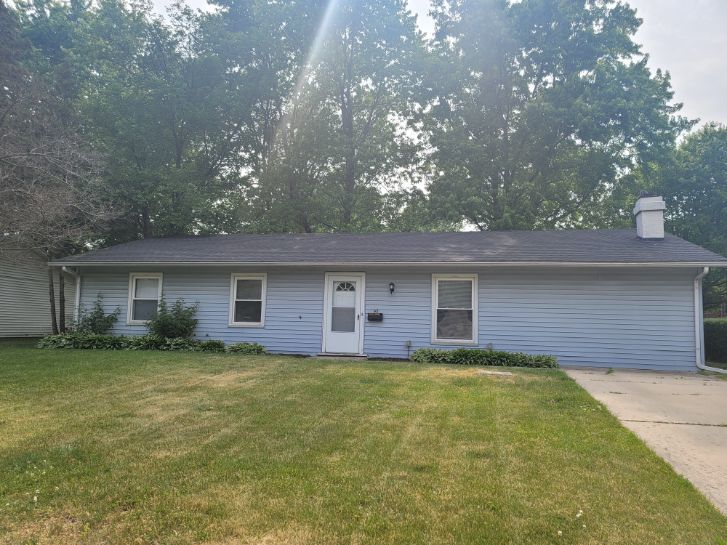 a brick house next to a yard with a large tree