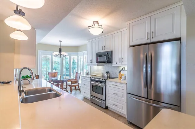 a kitchen with granite countertop a refrigerator a stove a sink cabinets and a dining table