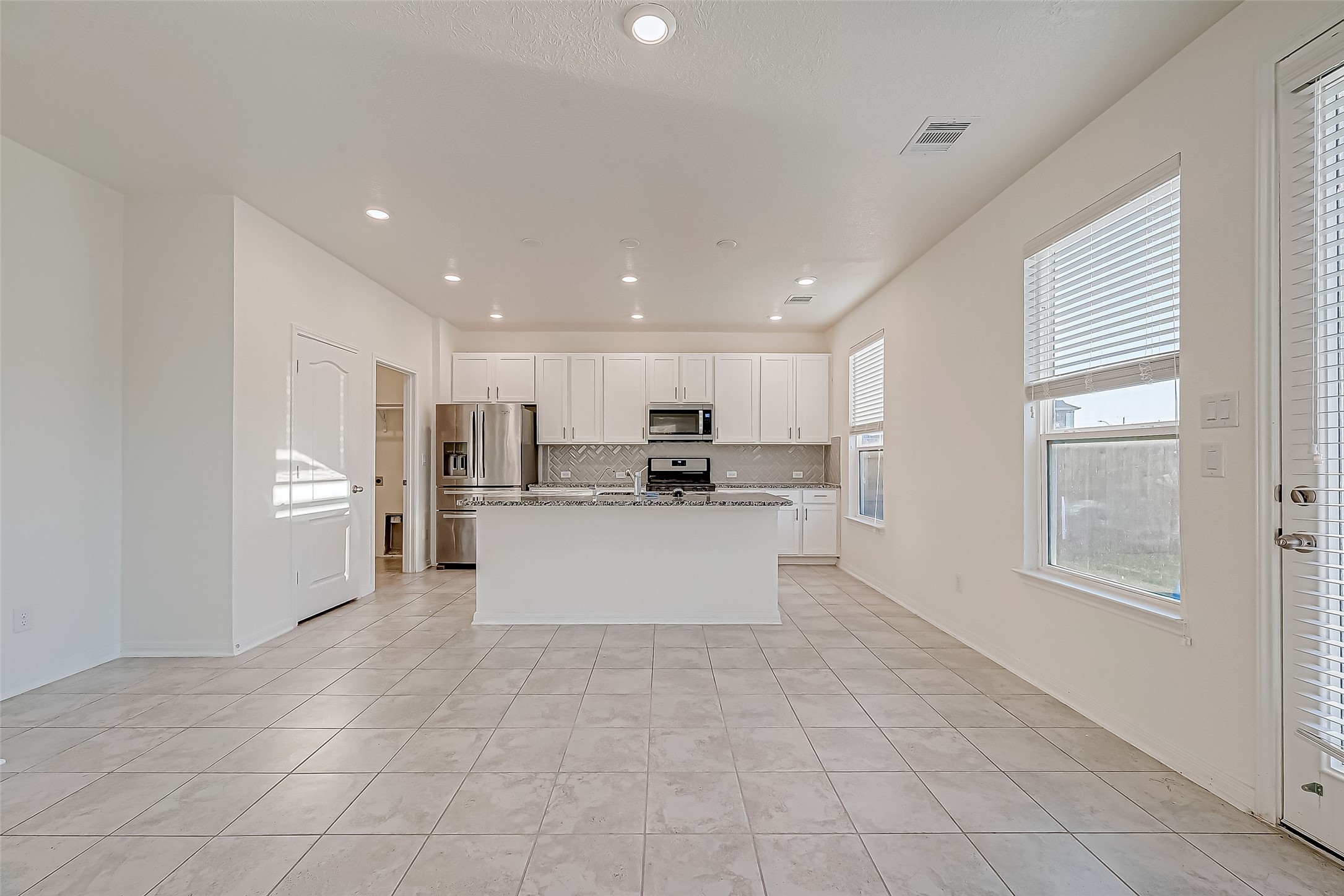 7106 Escondido Drive Rosharon, TX 77583 - Photo 9 of 41 a large white kitchen with kitchen island white cabinets and stainless steel appliances