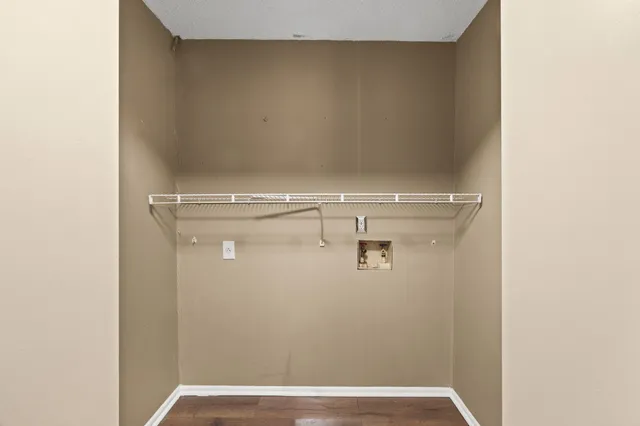 a view of a hallway with wooden floor and a bathroom