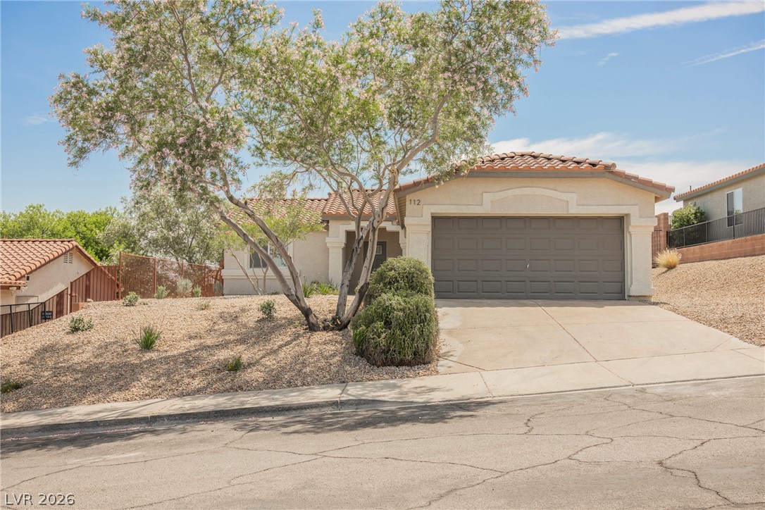 112 Iridescent Street Henderson, NV 89012 - Photo 5 of 24 A terracotta-roofed residence presents a neat desert landscape and an attached garage.