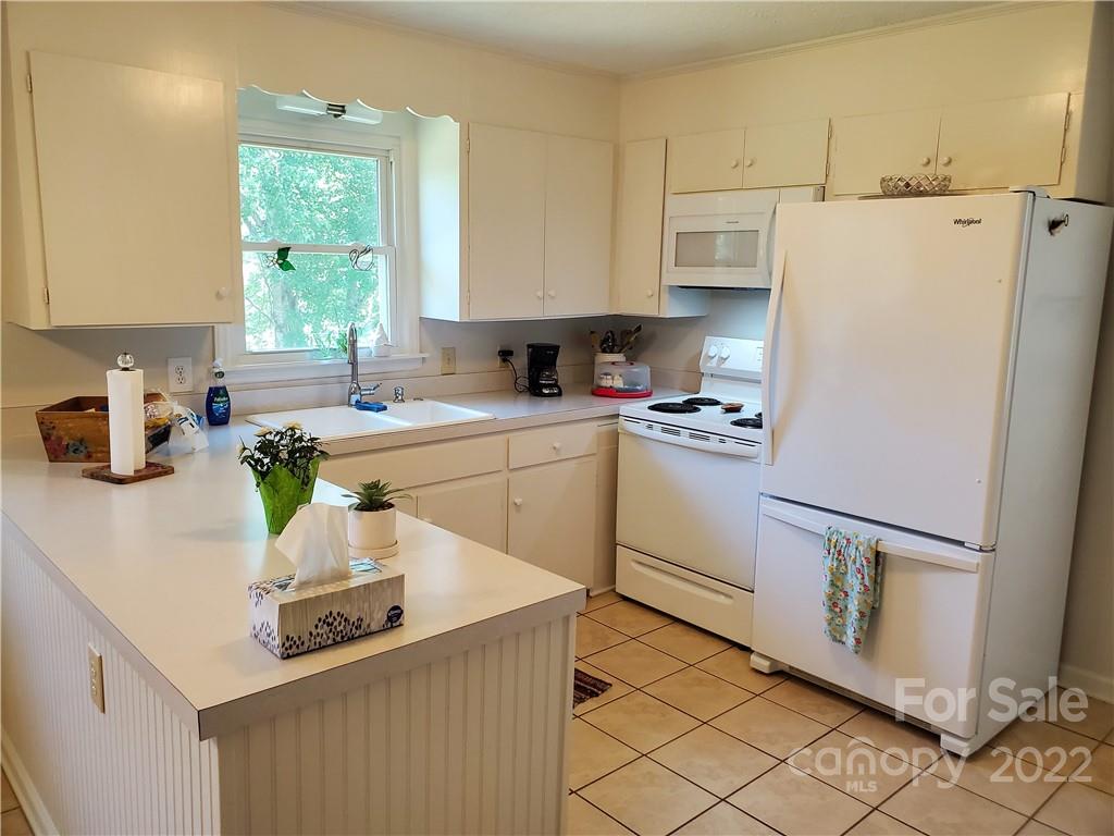 4681 Emerald Drive Morganton, NC 28655 - Photo 9 of 38 a kitchen with a sink a refrigerator a window and white cabinets