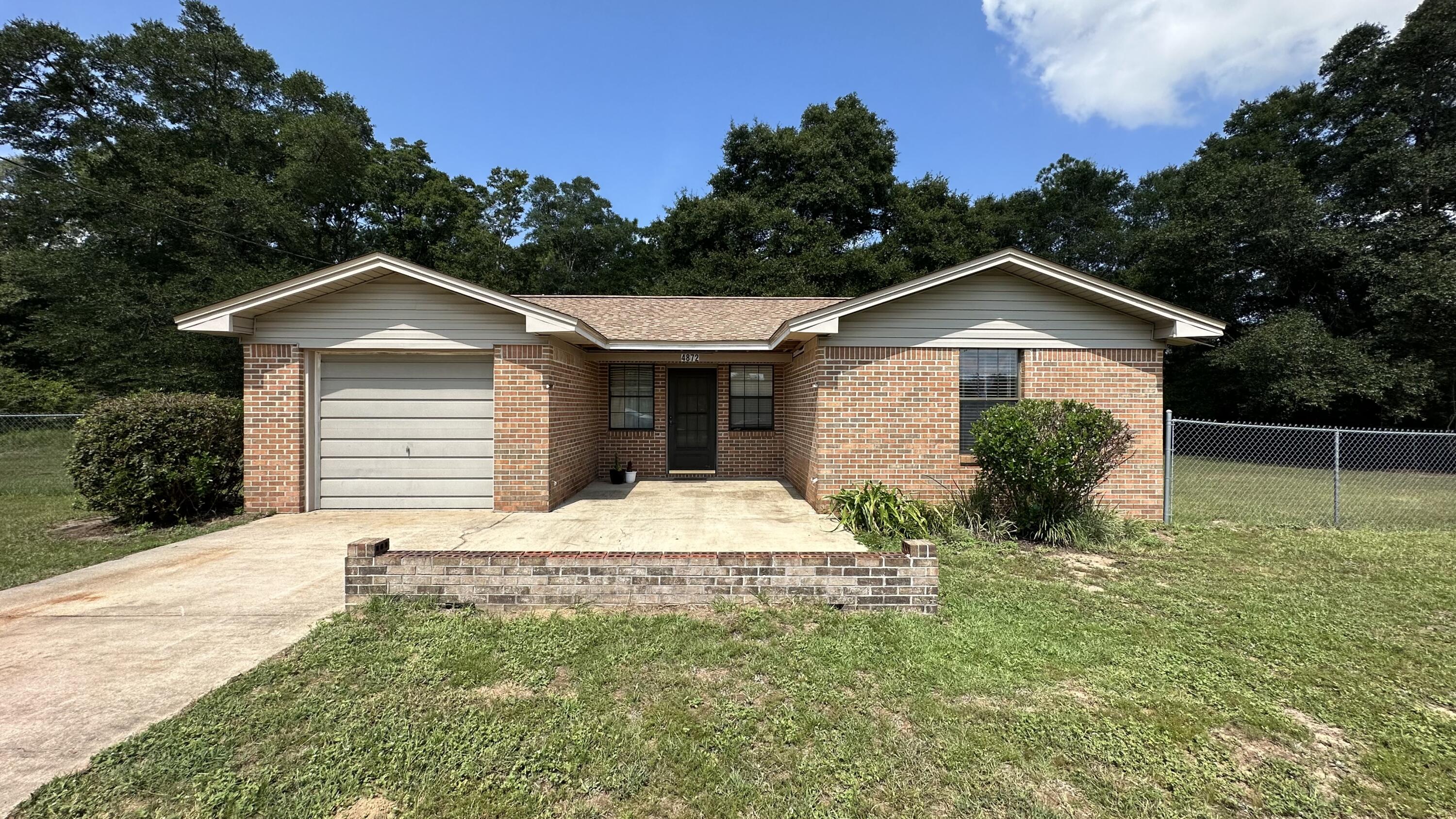 4872 Griffith Mill Road Holt, FL 32564 - Photo 1 of 15 a front view of a house with a yard and garage