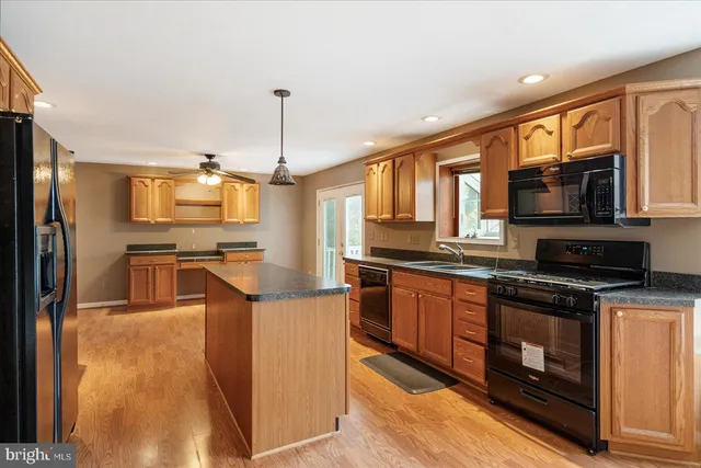 a kitchen with stainless steel appliances granite countertop a stove top oven a sink dishwasher a refrigerator and a microwave