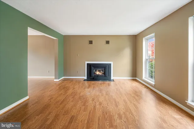 a view of empty room with wooden floor and fireplace