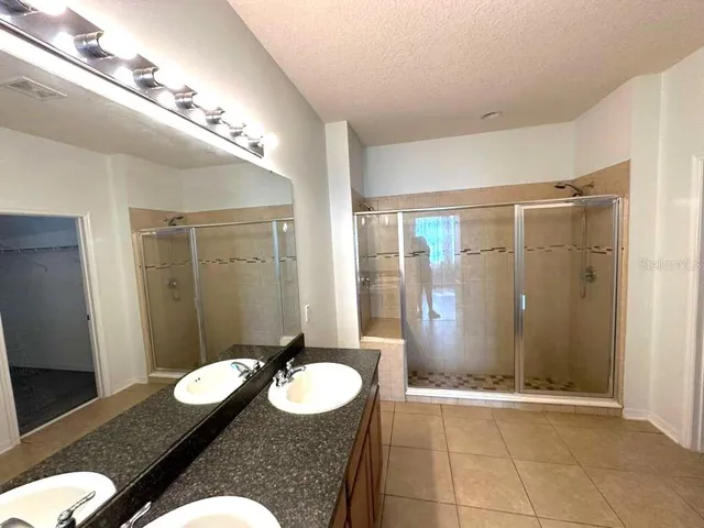 a bathroom with a granite countertop sink a mirror and a shower