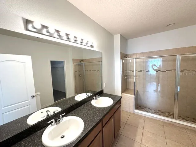 a bathroom with a sink shower and a mirror