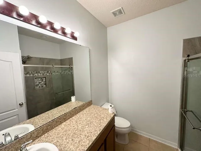 a bathroom with a granite countertop sink toilet and shower