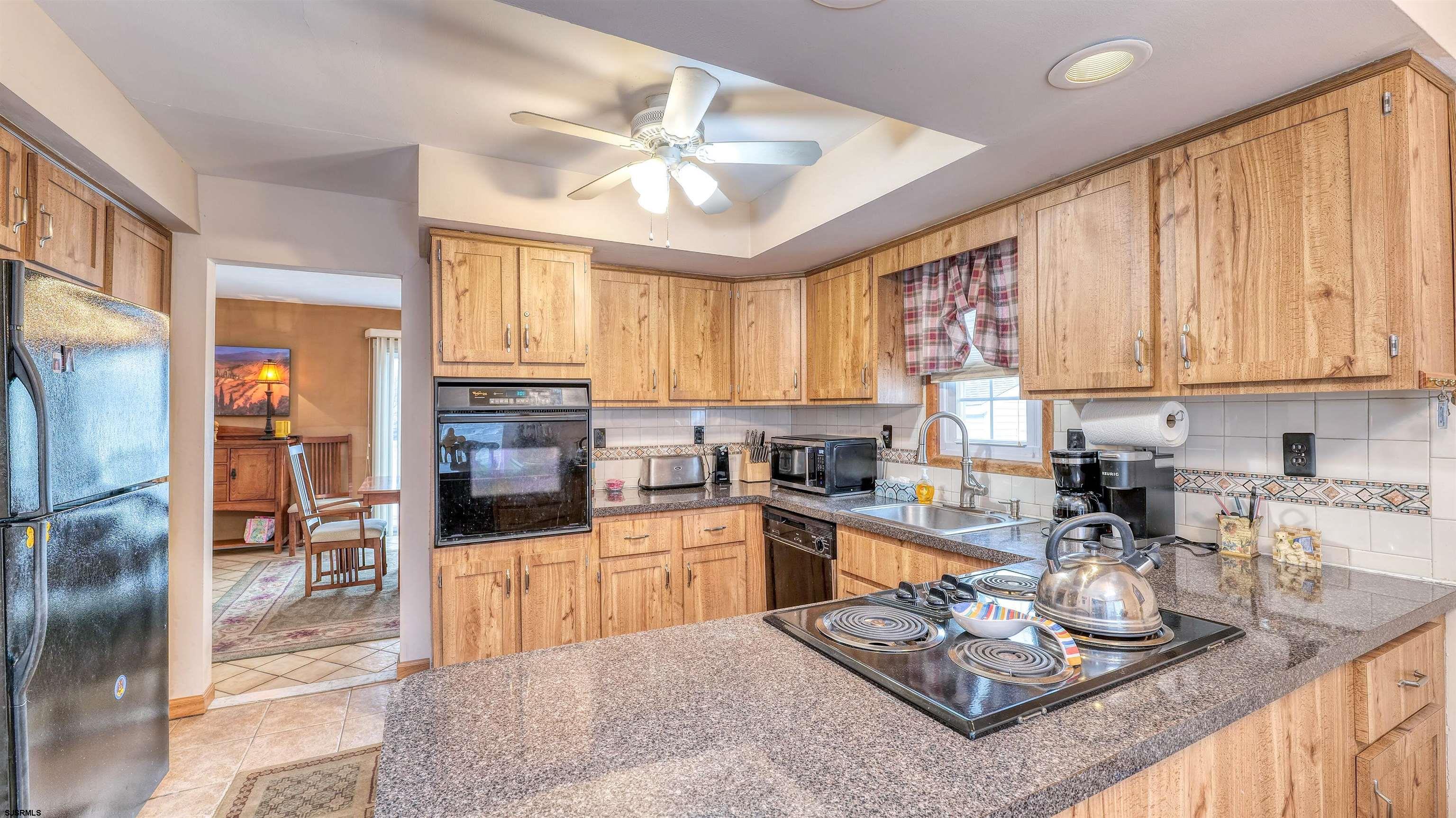 1330 Ouimet Road Brigantine, NJ 08203 - Photo 8 of 43 a kitchen with stainless steel appliances granite countertop a stove top oven a sink dishwasher a dining table and chairs with wooden floor