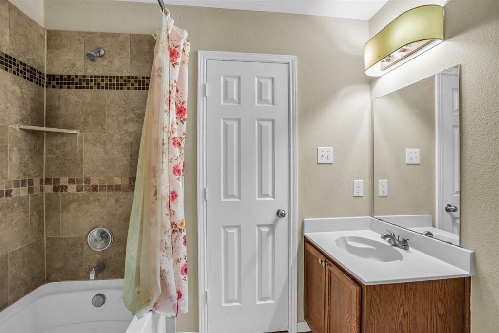 5718 Green Ivy Road Denton, TX 76210 - Photo 27 of 37 Bathroom vanity featuring a rectangular undermount sink, a white countertop, and a wood-finish cabinet