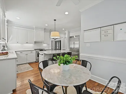 a kitchen with stainless steel appliances granite countertop a stove a sink a refrigerator and white cabinets with wooden floors