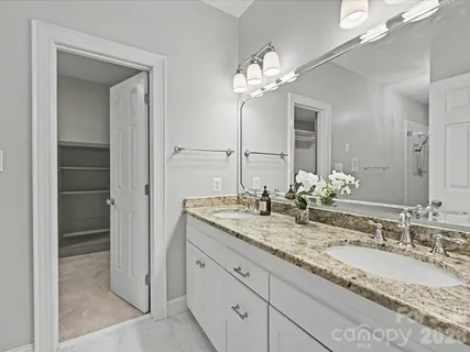 a bathroom with a granite countertop double vanity sink and a mirror