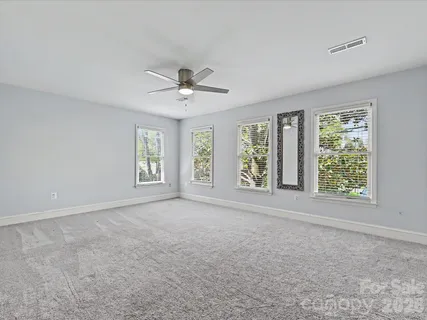 a view of an empty room with a window and a kitchen