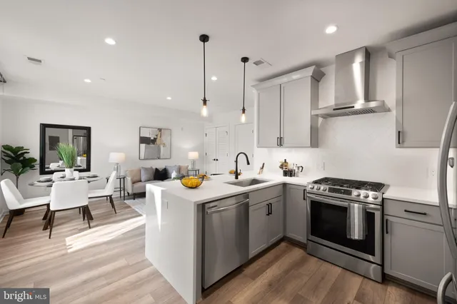 a kitchen with stainless steel appliances granite countertop a stove a sink dishwasher and a refrigerator with wooden floor