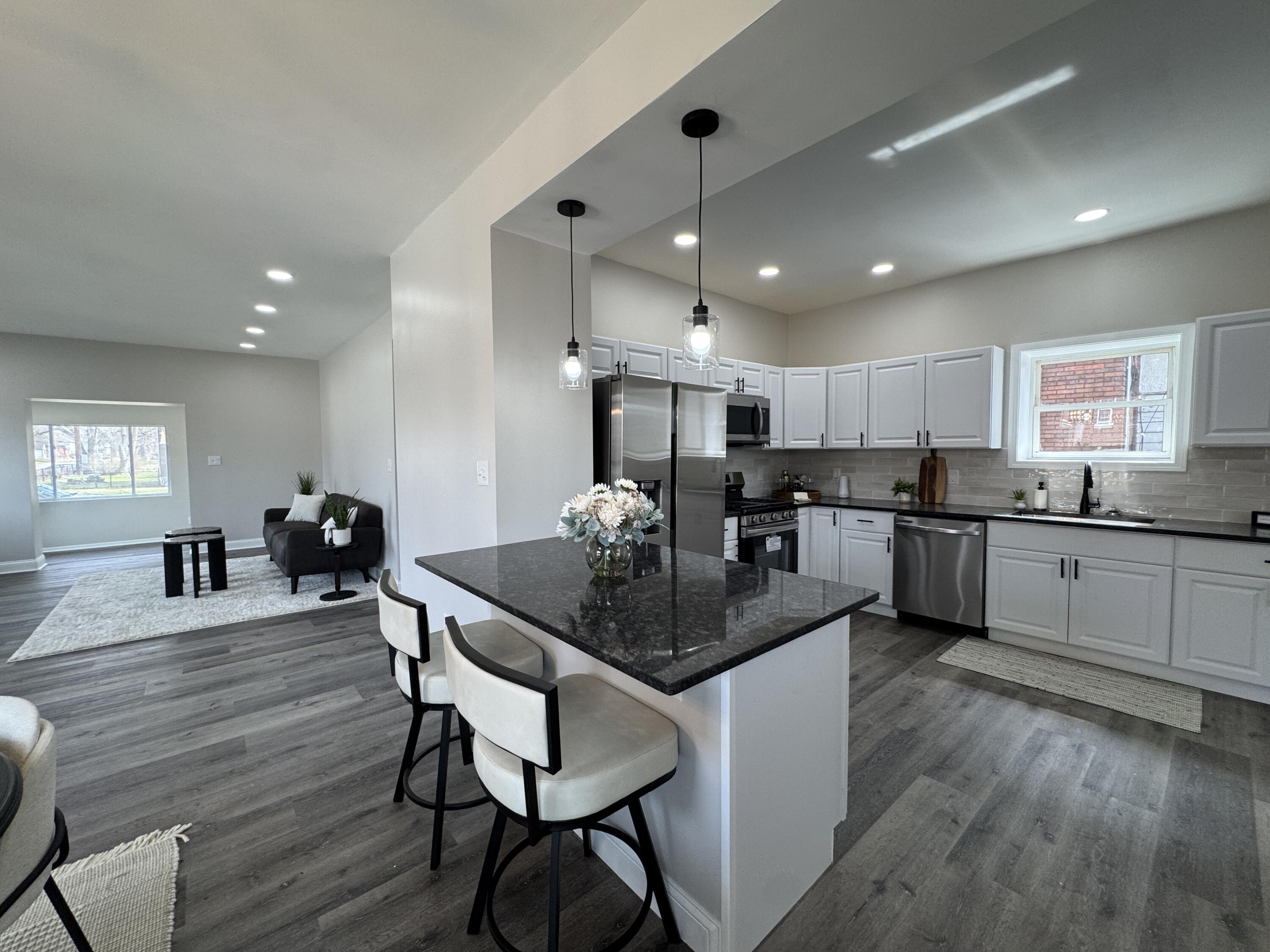 800 Buchanan Street Gary, IN 46402 - Photo 11 of 29 a kitchen with stainless steel appliances kitchen island granite countertop a stove a sink a refrigerator and white cabinets with wooden floor