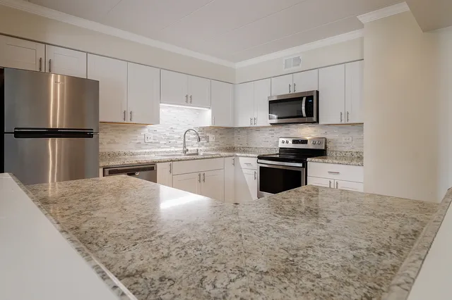 a kitchen with kitchen island a refrigerator sink and white cabinets