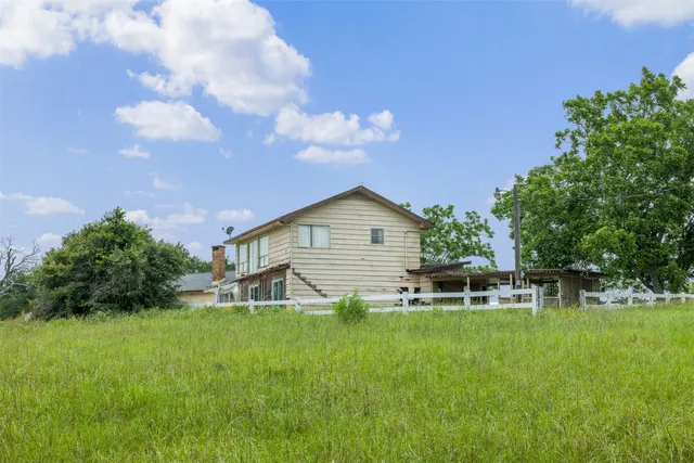 a backyard of a house with table and chairs plants and large tree