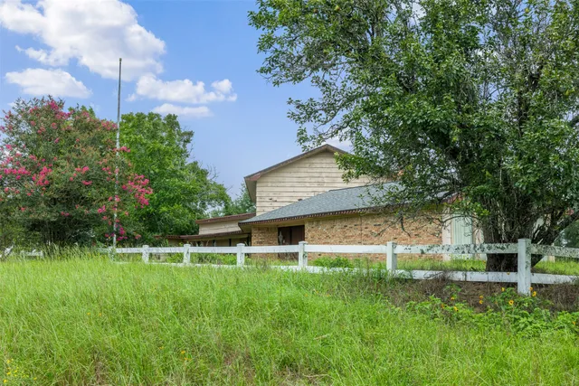 a view of a house with a yard and a large tree