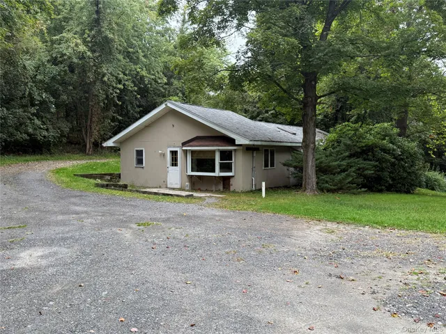 a view of a house with a yard and large trees