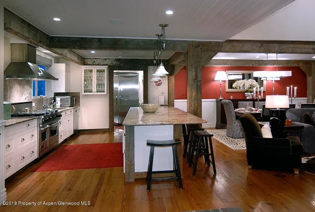 a kitchen with stainless steel appliances granite countertop a stove a refrigerator a kitchen island with a dining table and chairs