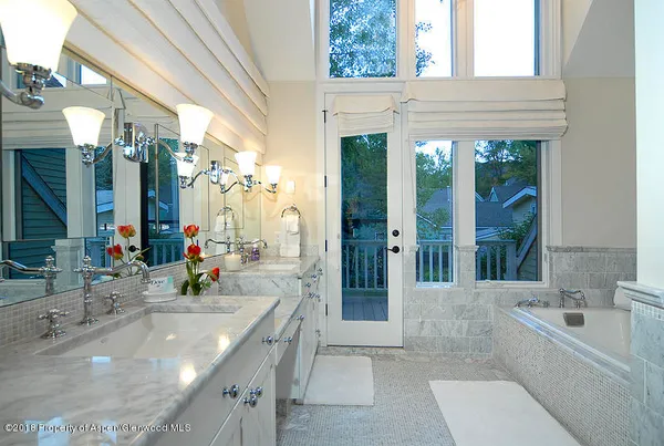 a bathroom with a granite countertop tub sink and mirror