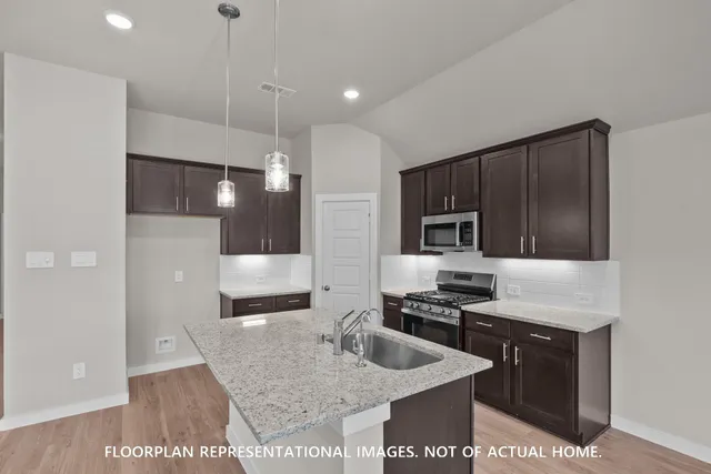 a kitchen with stainless steel appliances granite countertop a sink a stove and a refrigerator