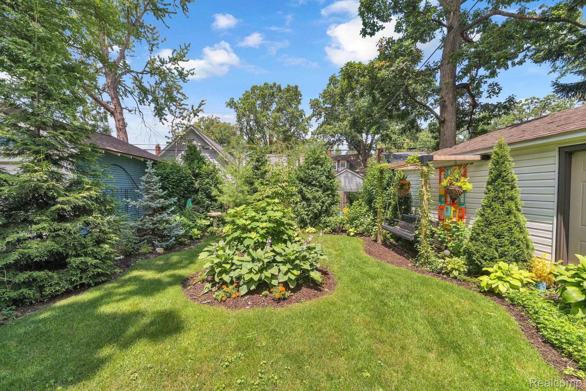 21 Devonshire Road Pleasant Ridge, MI 48069 - Photo 5 of 35 Landscaped backyard featuring a manicured lawn, established garden beds, and mature trees