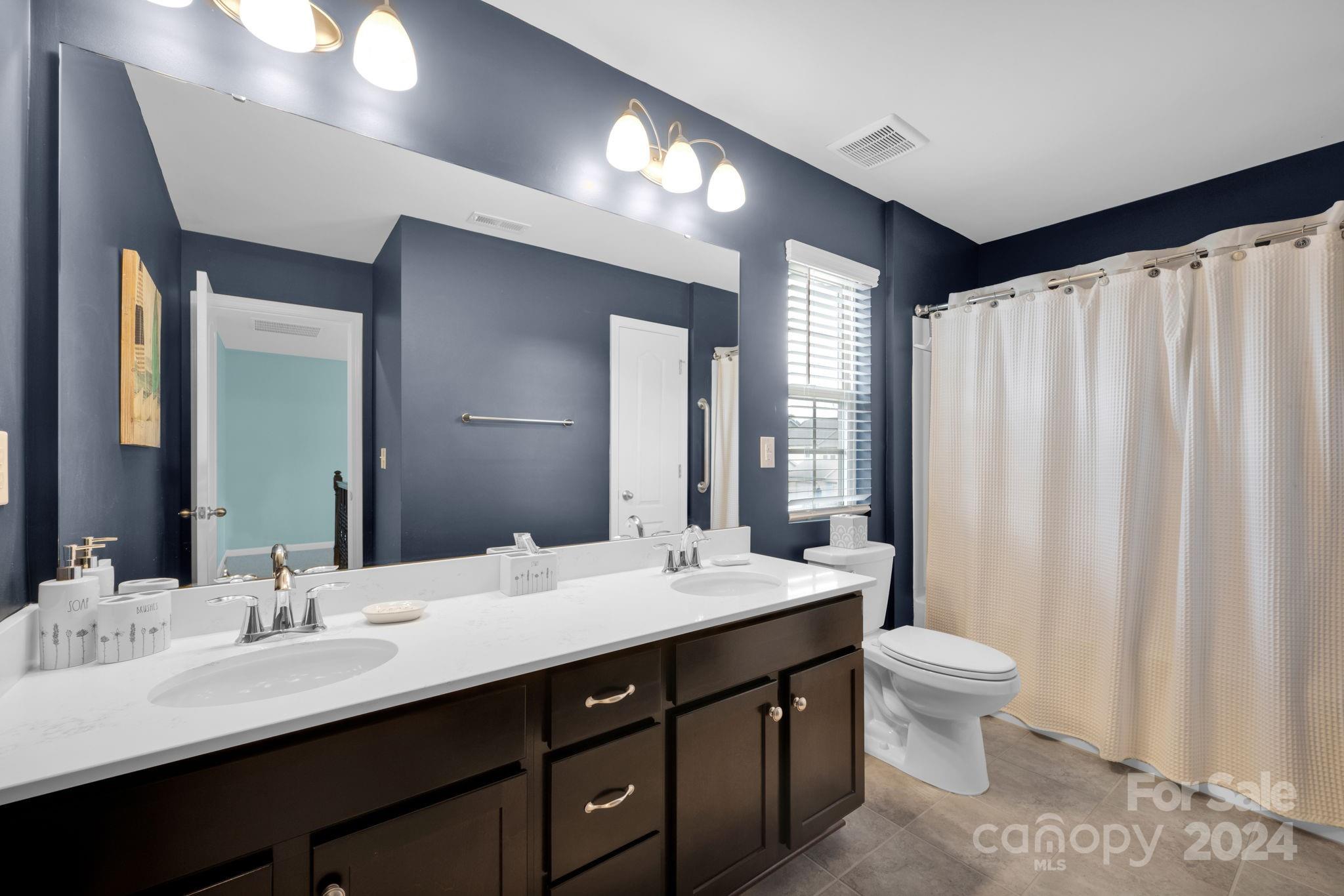 12834 Robert Walker Drive Davidson, NC 28036 - Photo 21 of 27 a bathroom with double vanity sinks a toilet a mirror and vanity