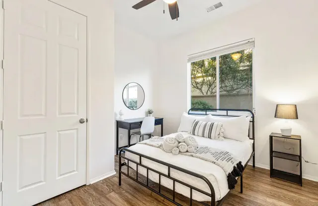 a bedroom with a bed a mirror and a large window