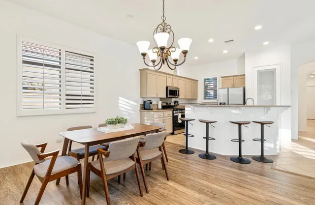 a dining room filled chandelier and wooden floor