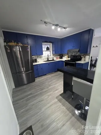 a kitchen with stainless steel appliances granite countertop a refrigerator a sink dishwasher a stove and a refrigerator with wooden floor