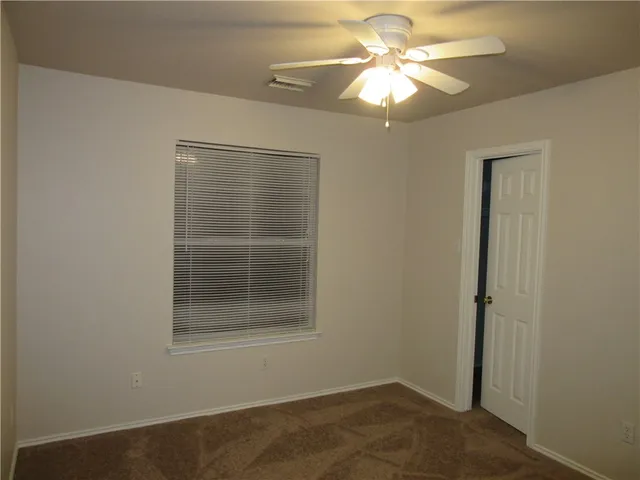 an empty room with a window and a fan