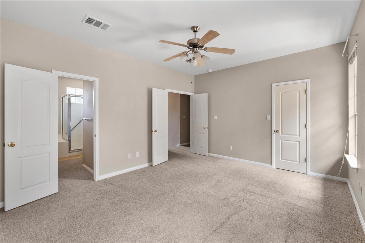 11000 Anderson Mill Road, Unit 11 Austin, TX 78750 - Photo 12 of 34 A spacious primary bedroom featuring plush carpeting and a modern ceiling fan.