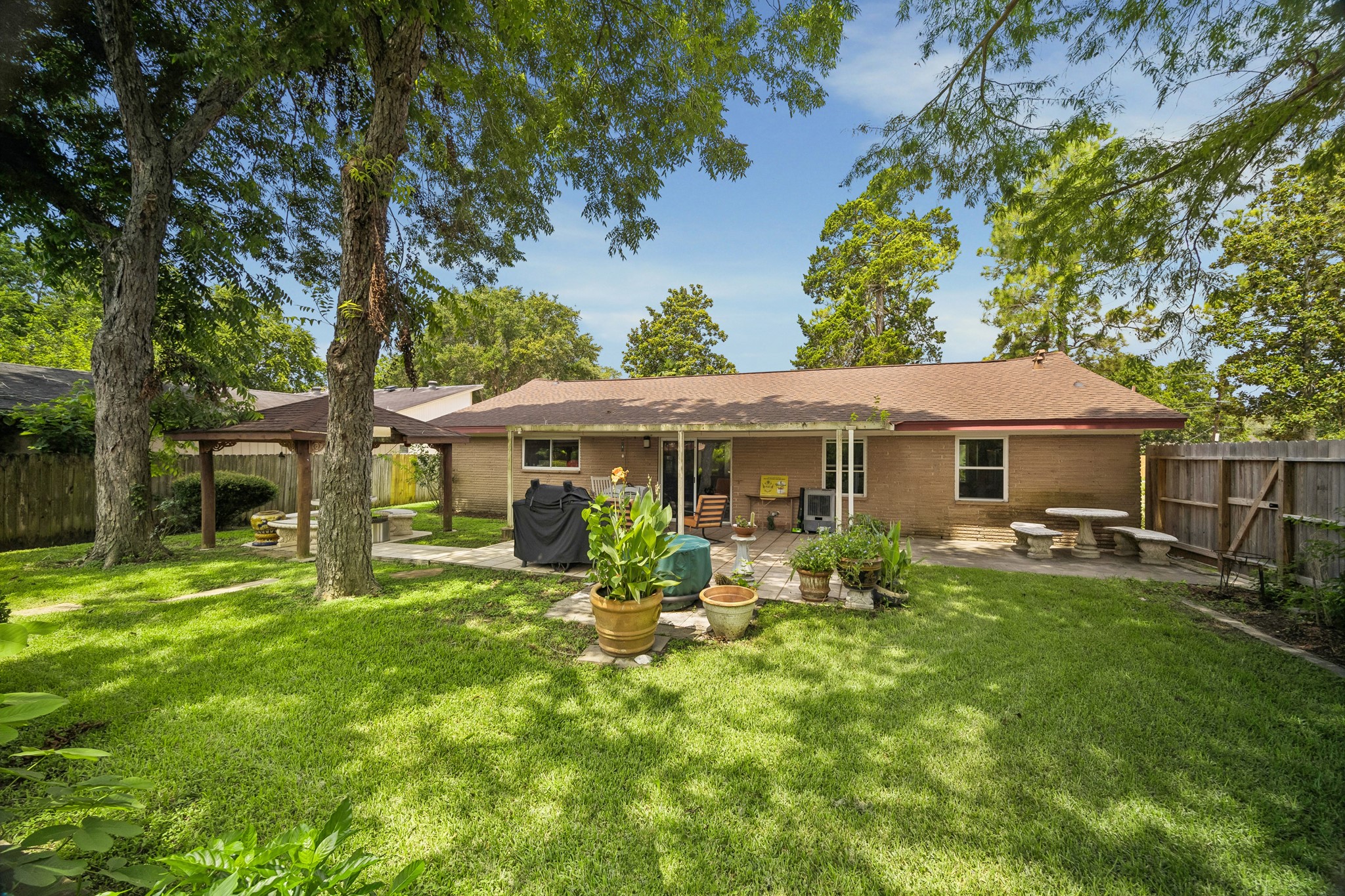 413 Mebane Lane Rosenberg, TX 77471 - Photo 5 of 30 This backyard features a spacious grassy area with mature trees providing shade. The covered patio is the perfect place for outdoor entertaining. There is additional lawn space to enjoy on the other side of the wooden fence.