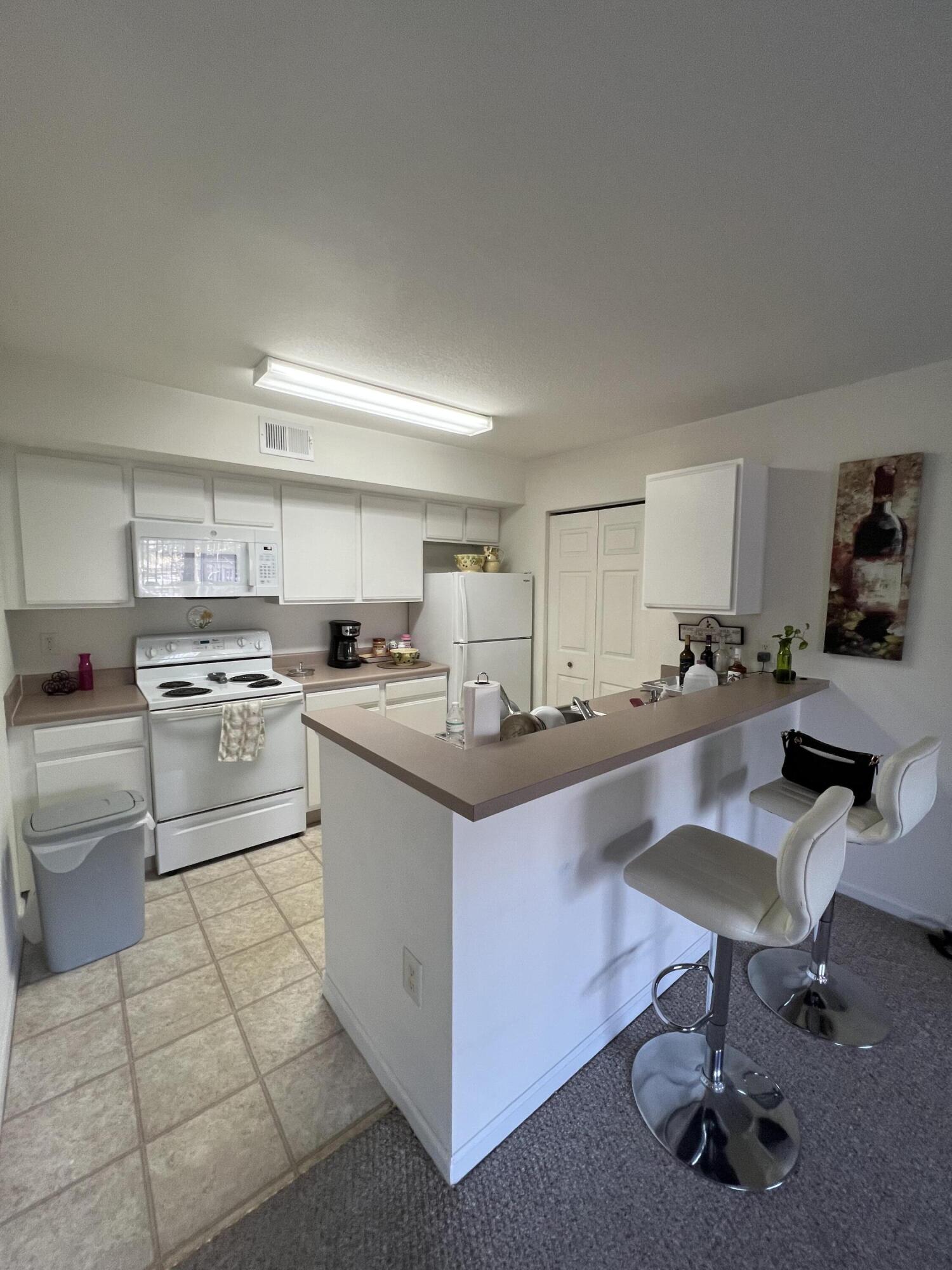 131 Southwest Palm Drive, Unit 203 Port St. Lucie, FL 34986 - Photo 3 of 13 a kitchen with kitchen island a sink stove and white cabinets